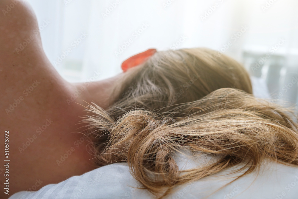 Portrait of young woman lying in bed, back view. Wild hair on pillow in morning sun rays. Tenderness and good morning concept, close up Portrait of young woman lying in bed, back view. Wild hair on pillow in morning sun rays. Tenderness and good morning concept, close up