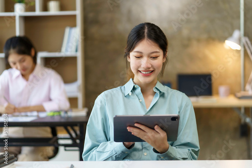 Portrait of young Asian business woman using digital tablet in the office.