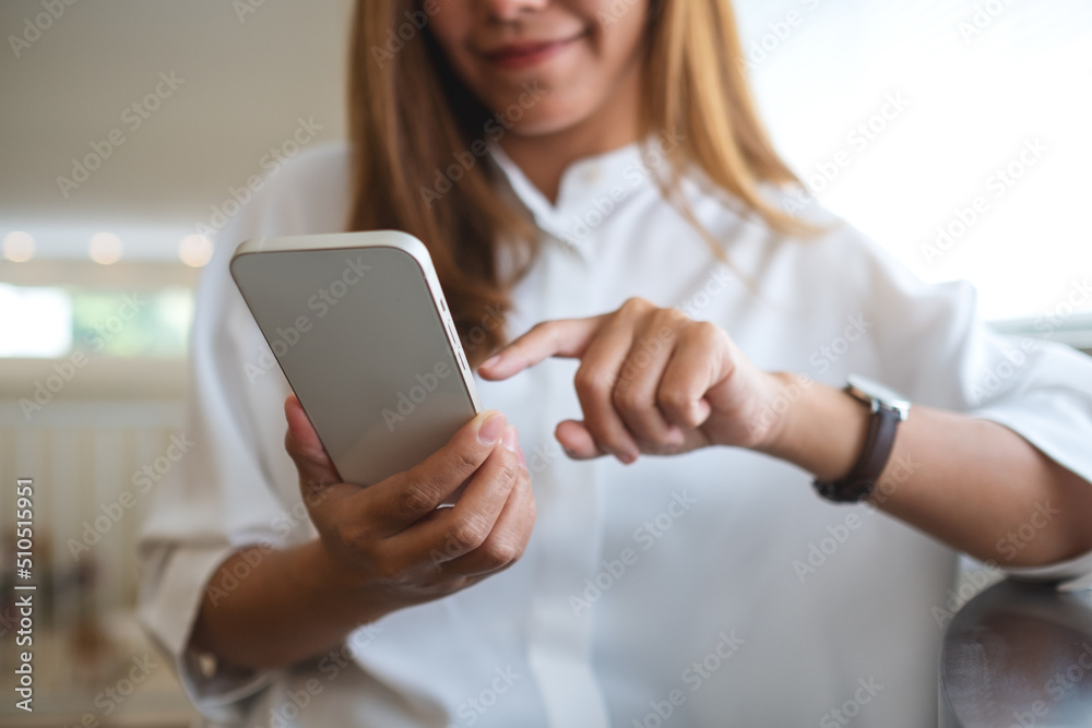 Closeup image of a young woman holding and using mobile phone
