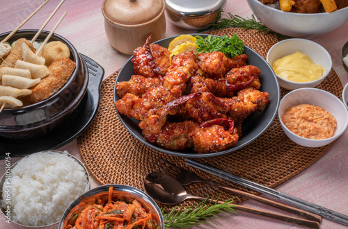 Gang Jeong chicken or crispy and tender Korean fried chicken smothered in a sticky, spicy red sauce Served with kimchi, dipping sauce, rice and sweet corn. photo