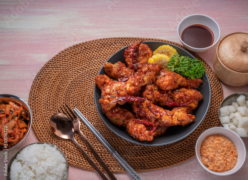 Gang Jeong chicken or crispy and tender Korean fried chicken smothered in a sticky, spicy red sauce Served with kimchi, dipping sauce, rice and sweet corn. photo