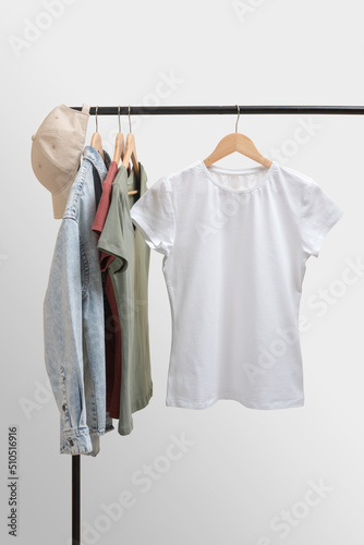 Blank white female t-shirt mockup. Basic women`s clothes. Woman collection of clothes on a rack. Spring and summer fashion trending concept. Railing with stylish female clothes