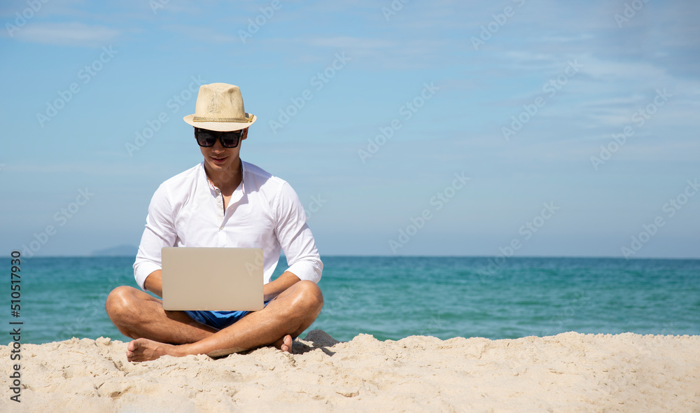 Handsome relaxed man using laptop, beach background, freelance working social on holiday summer. Summer and Vacation Concept