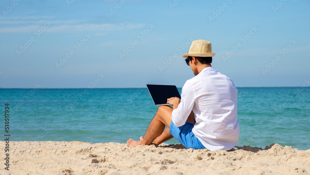 Handsome relaxed man using laptop, beach background, freelance working social on holiday summer. Summer and Vacation Concept