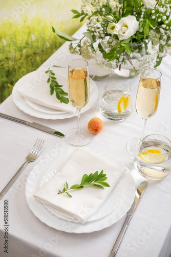 Wedding teble decoration with white flowers, glasses and white napkins. Elegantly decorated table at a wedding reception. Festive table setting. The wedding decor.