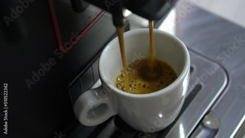 Preparation of espress in automatic coffee machine, adding black espresso. Coffee puring into cup