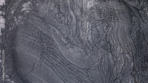 Abstract fluid background design of moving monochrome liquid silver shimmering ink. Lava flow, melting and seething of metals