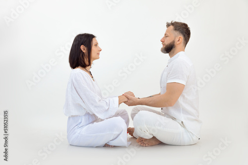 Man and woman, couple in love, wear white outfit, practice Pilates and yoga, sit in lotus pose. Conscious tantra love photo