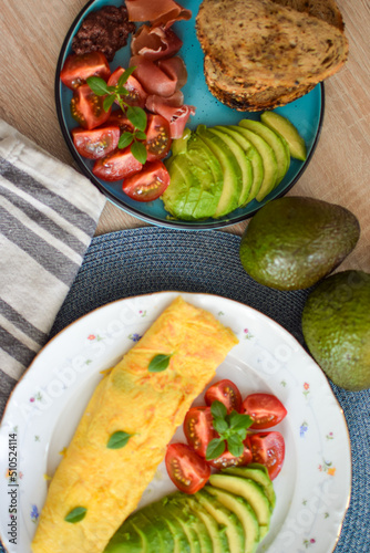 French omelet filled with cheese. Plating with avocado and cherry tomatoes.