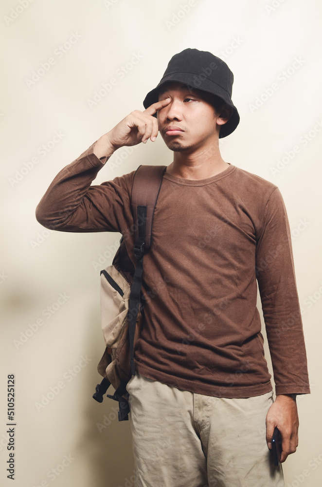 Portrait of sad young Asian boy wearing black hat carrying backpack for travel isolated on background Portrait of sad young Asian boy wearing black hat carrying backpack for travel isolated on background