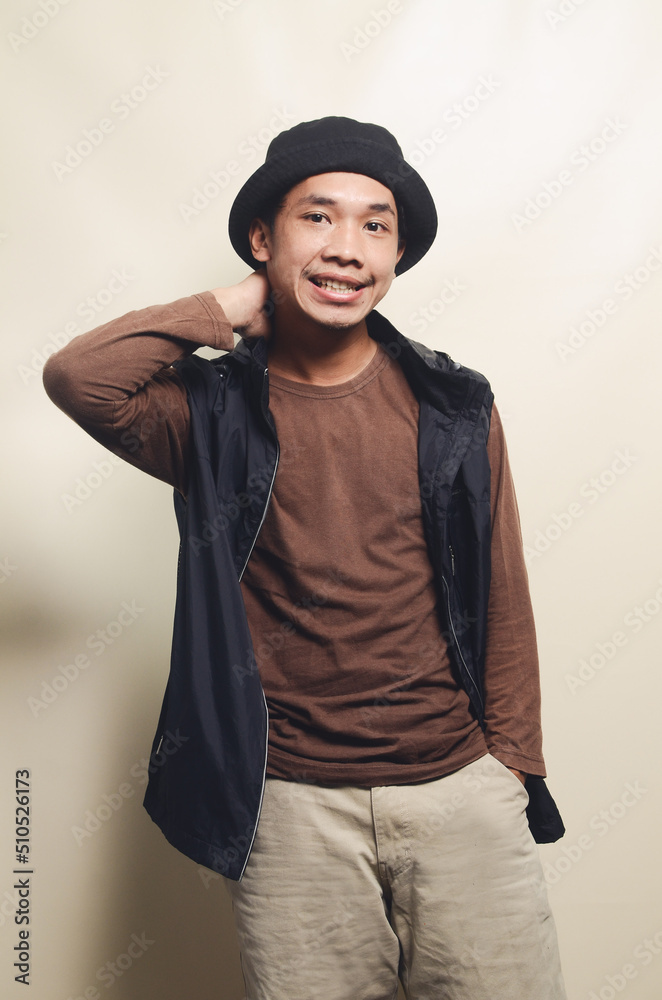 Portrait of Asian college young man with greeting gesture wearing brown t-shirt and black vest Portrait of Asian college young man with greeting gesture wearing brown t-shirt and black vest