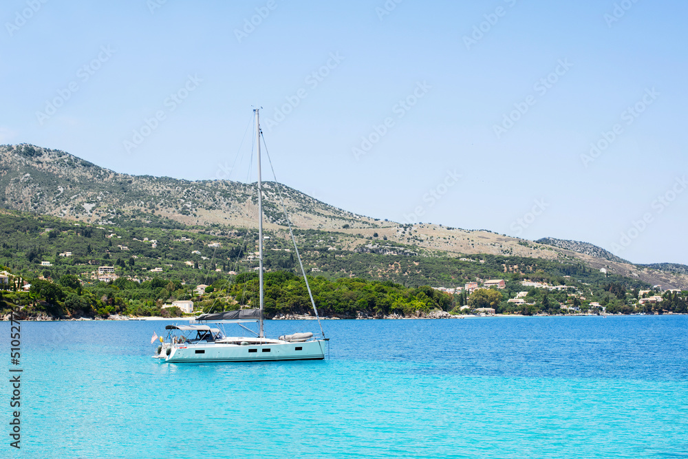 Beautiful bay with sailing boat yacht, Corfu island, Greece. Picturesque greek seascape. Yachting, travel, vacations, summer fun, enjoying life and active lifestyle concept