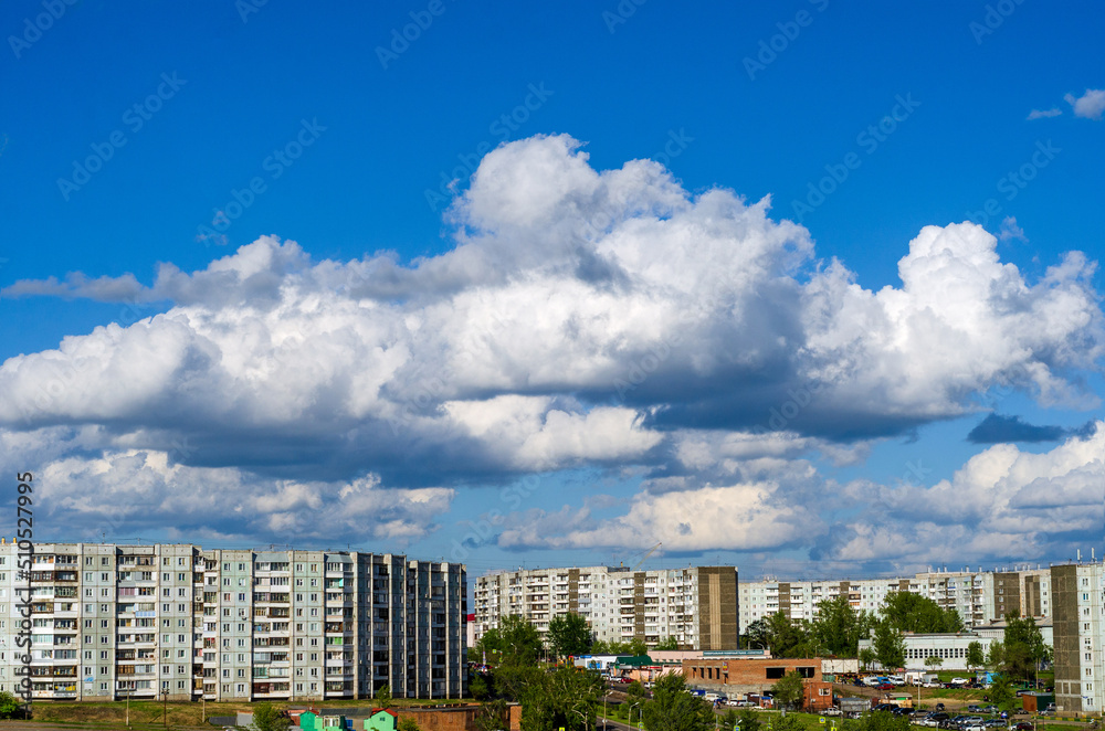 white clouds in the blue summer sky over the city