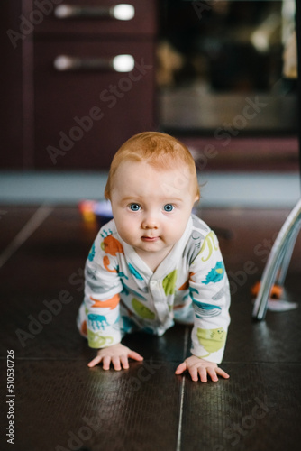 Baby boy crawling on the floor in nursery room at home. Baby health care and family concept.