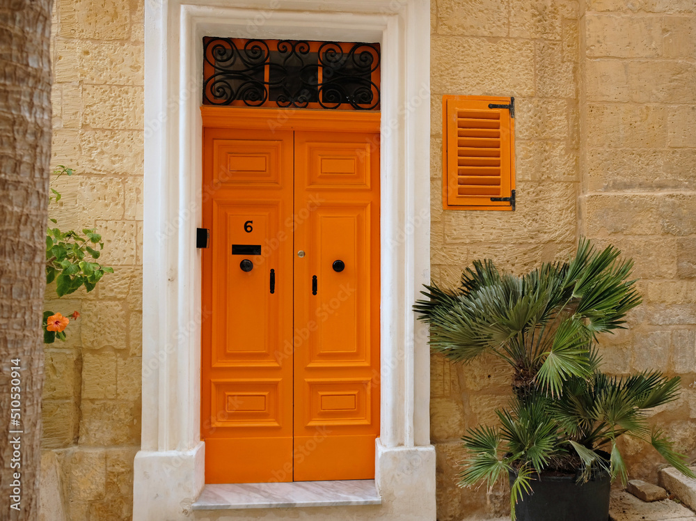 Fototapeta premium Traditional vintage painted wooden door in Malta. Popular travel destination. Entrance to house. Exterior of typical houses on the Mediterranean island of Malta - April, 2022.