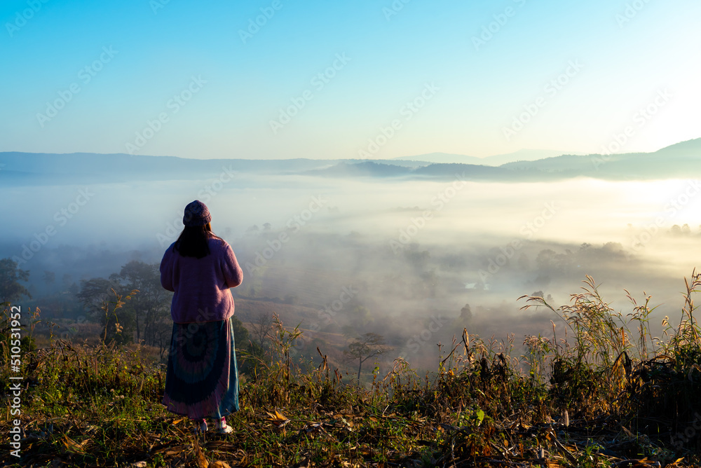 Traveler Asian woman enjoying and relaxing on the mountains view containing calm, fog, and mist in the morning.