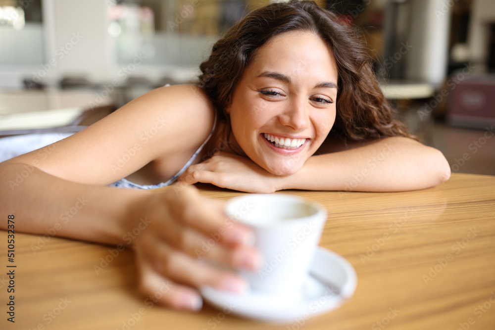 Happy woman holding a coffee cup in a bar