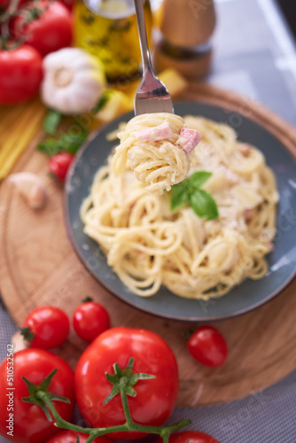 homemade pasta carbonara with fresh basil and parmesan in ceramic dish