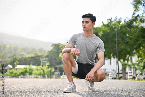 Portrait of young athletic asian man in an active sportswear on the running sidewalk