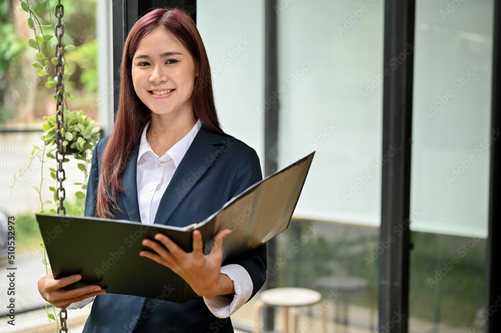 Obraz premium Portrait of a beautiful young asian businesswoman in formal suit with a document folder