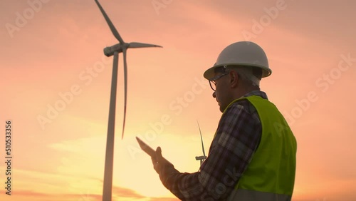 Windmill engineer watching wind turbines in operation on a tablet