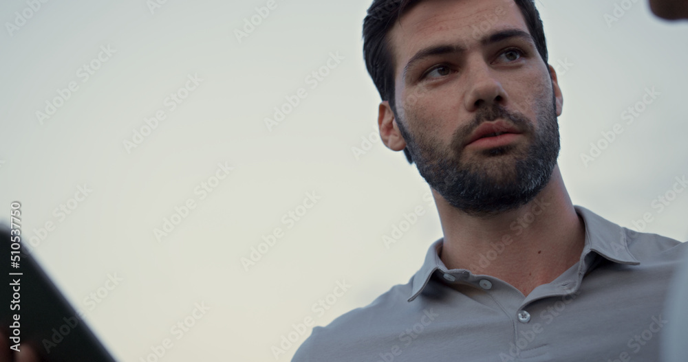 Obraz premium Man face looking tablet screen outdoors. Sexy guy talking online on golf course.