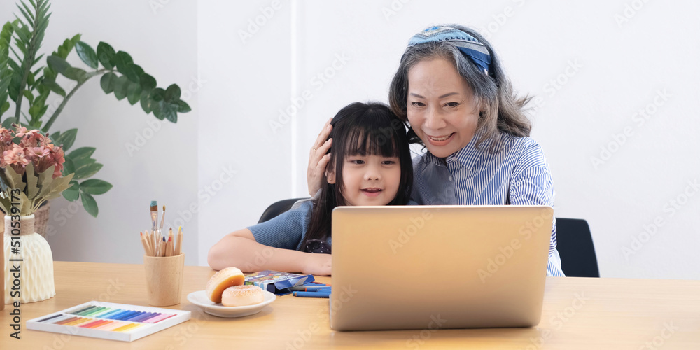 Asian grandmather teach granddaughter drawing and doing homework at home. Asian grandmather teach granddaughter drawing and doing homework at home.