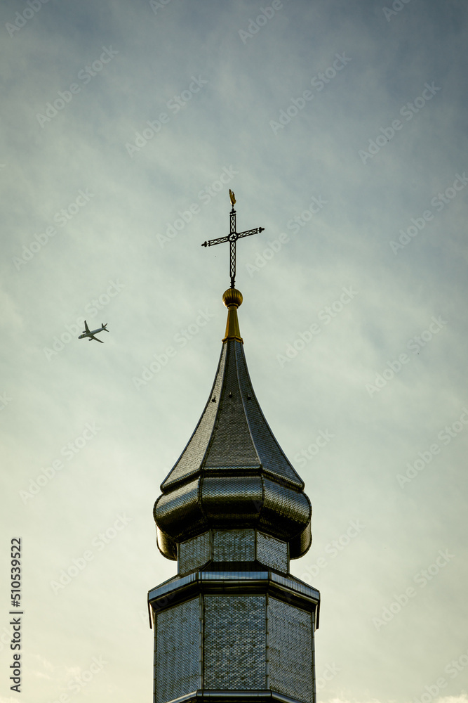 Clocher d'église avec un avion qui passe
