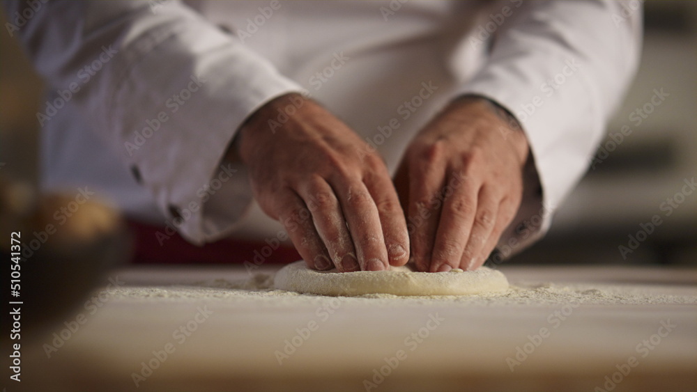 Pastry cook hands knead pizza dough on board. Chef man making bread in kitchen.