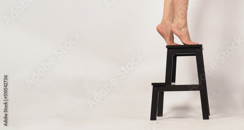 Φωτογραφία Legs and Barefoot stand on tiptoe on a step stool or wooden stairs with white background