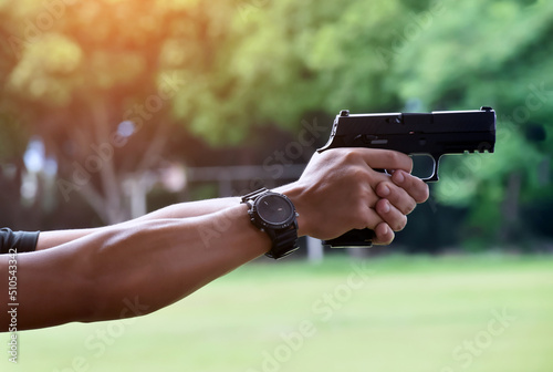 9mm automatic pistol holding in right hand of shooter, concept for security, robbery, bodyguard, gangsters, mafias, and police officers around the world. selective focus on pistol.