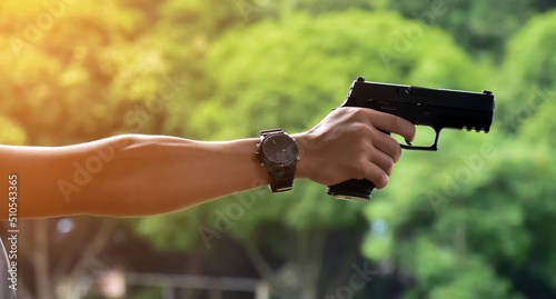 9mm automatic pistol holding in right hand of shooter, concept for security, robbery, bodyguard, gangsters, mafias, and police officers around the world. selective focus on pistol.
