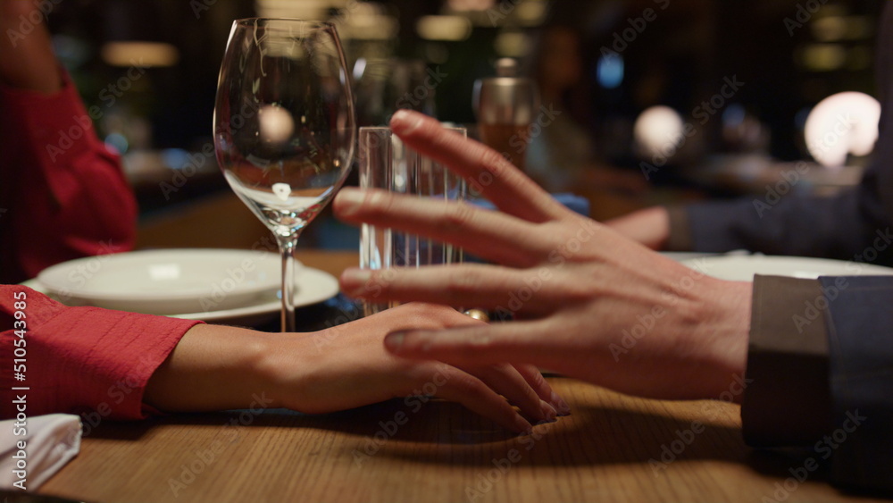Romantic couple holding hands in luxury interior restaurant. Dating concept.