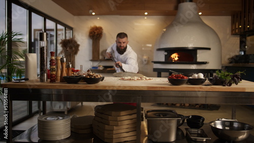 Chef cook preparing pizza in kitchen. Man taking food in restaurant stone oven. photo