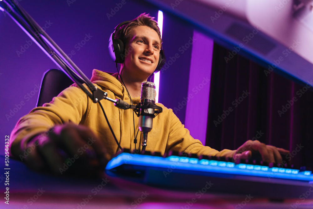 Happy professional player streaming esport tournament using microphone and  headphones, enjoying a multiplayer game. Competitive gamer playing online  video game at home. Neon color. Cyber sport concept Stock Photo