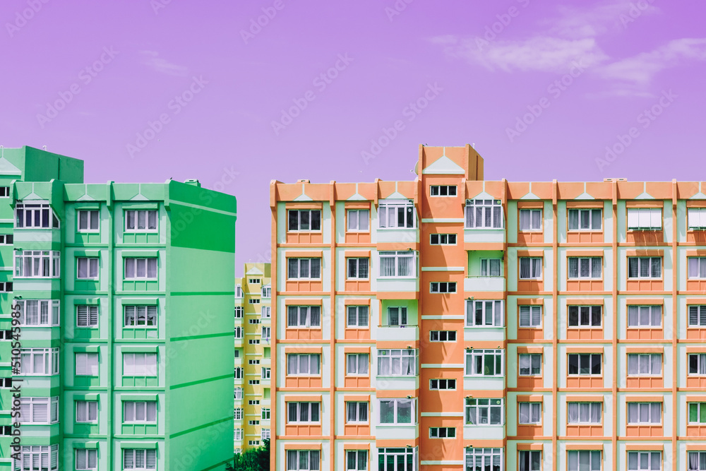 Green and orange panel building architecture houses on purple sky background. Nine-story old urban residential houses with windows