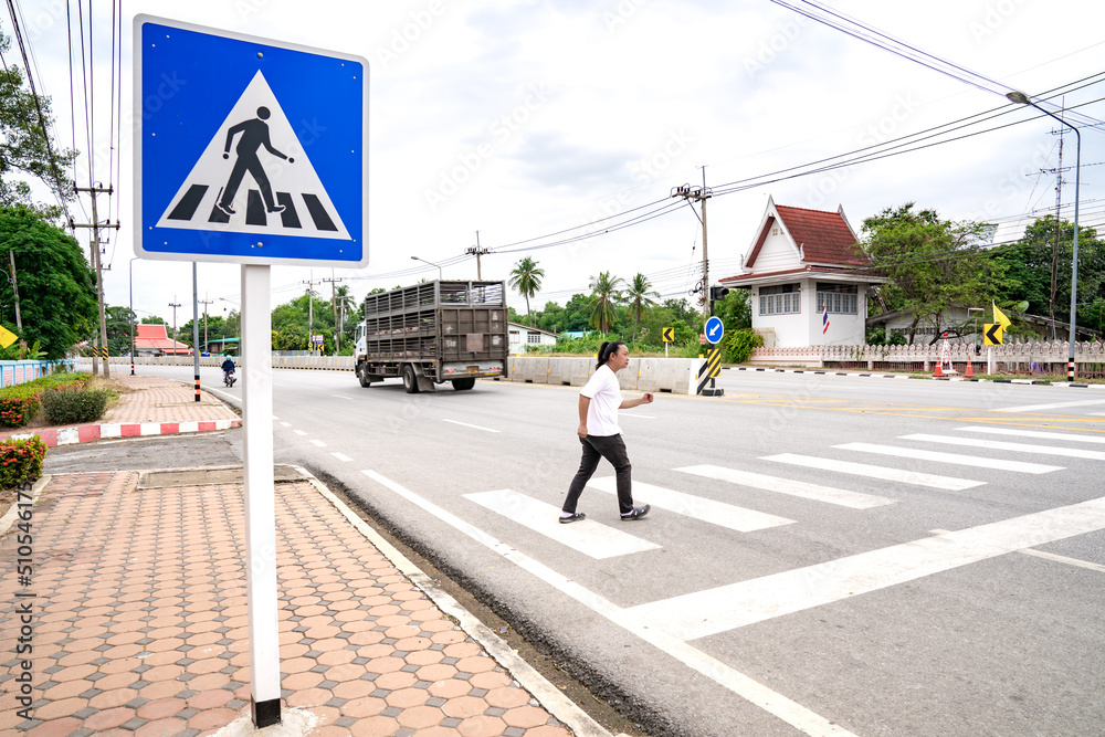 An Asian man prepares himself to walk and run across crosswalk to the other side, Thailand. An Asian man prepares himself to walk and run across crosswalk to the other side, Thailand.