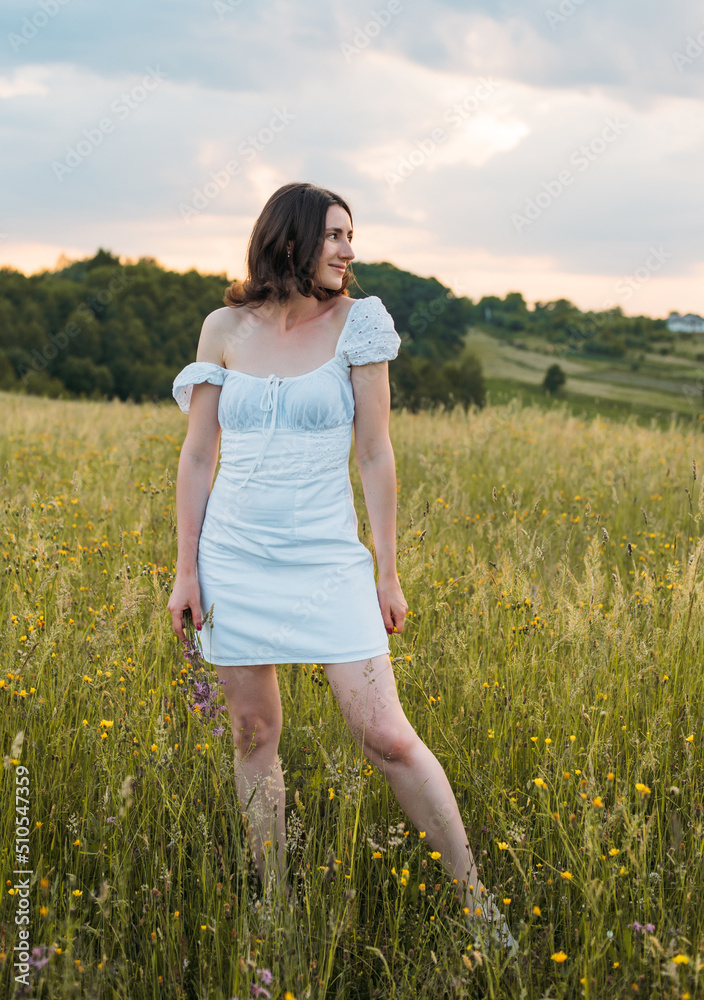 young happy female walking in the field enjoying beautiful sunset. Beautiful countryside. Slow living concept young happy female walking in the field enjoying beautiful sunset. Beautiful countryside. Slow living concept