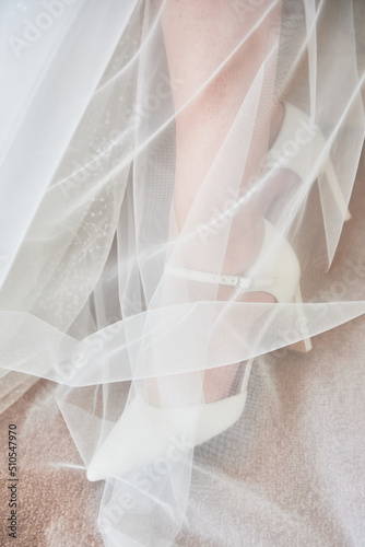 Close up of bride's feet in shoes with high heels under veil, copy space. Woman legs, close up.