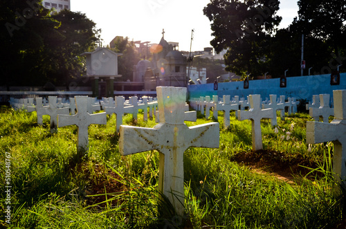 The line of holy crosses dug in the mud for the remembrance of the dead Christian people in the churchyard. Several white crosses with holy rosary in the graveyard. Mourning in the Day of the dead
