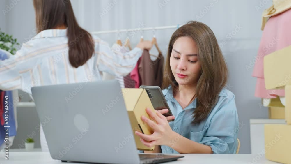 Asian two beautiful woman packing clothes order into box for customer. Asian two beautiful woman packing clothes order into box for customer.