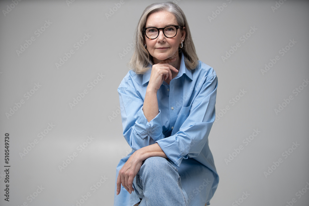 Maturity and style of adult woman. Fashionable mature female sitting on a chair sitting on a chair. Maturity and style of adult woman. Fashionable mature female sitting on a chair sitting on a chair.