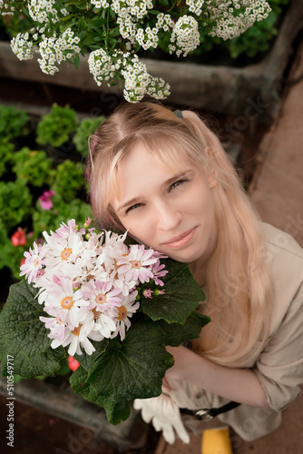 Young woman with pink and blond hair holding pink flowers in garden