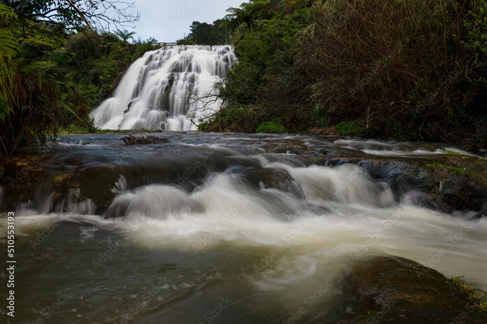 Obraz premium Owharoa Falls with water flowing downstream in the foreground, Karangahake Gorge, New Zealand.
