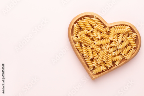 Pasta in a heart shaped wood bowl.