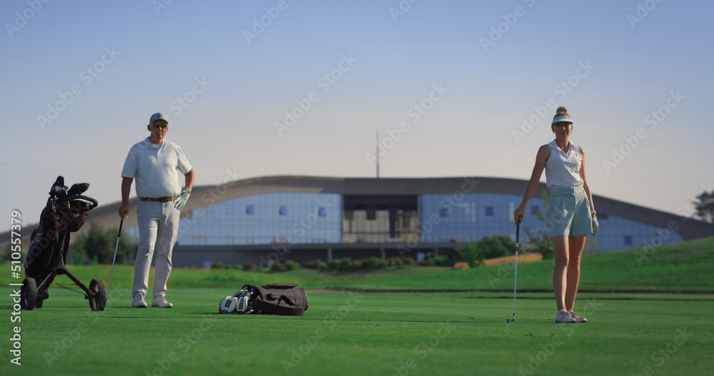 Obraz premium Luxury golfers enjoy play on fairway outdoors. Sport group stand on green course