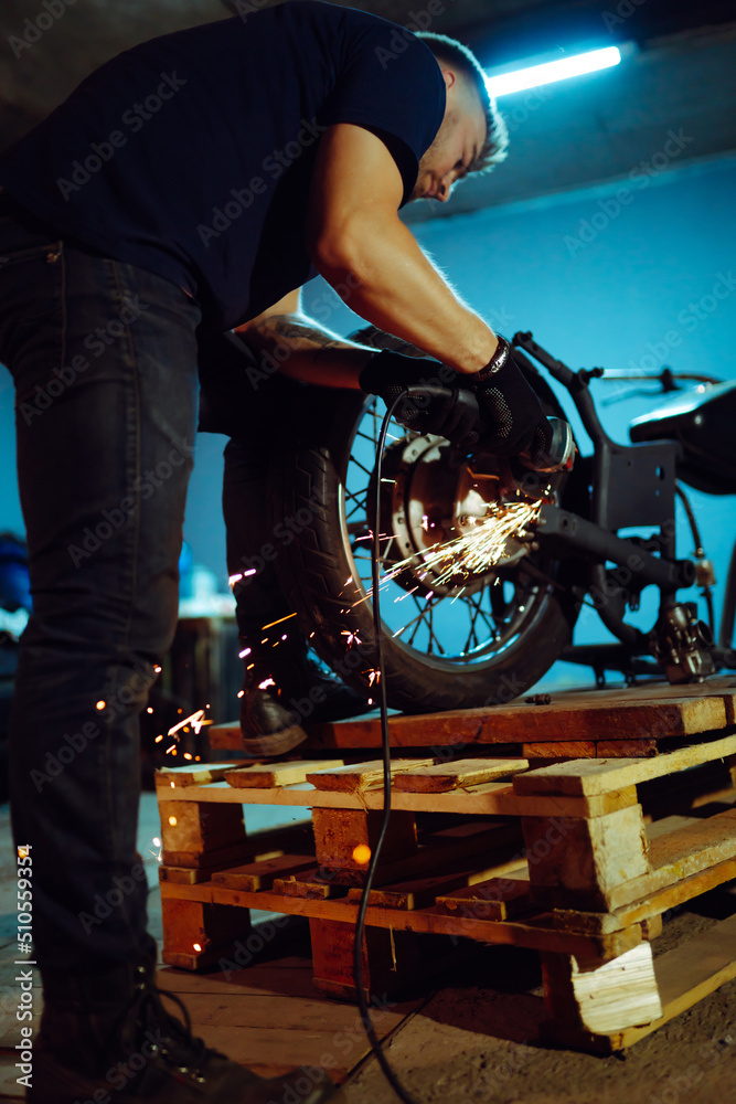 Motorcycle repair. Young man repairing motorbike in garage. Mechanic fixing motorcycle engine.