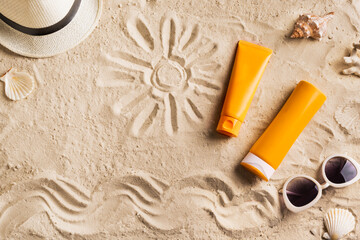 Sunblock, sunglasses and hat on summer sandy beach