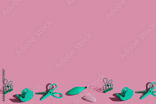 Flat lay frame composition with school green stationery supplies on pink pastel background. Vivid color minimal overhead shot with copy space. Back to school concept. Top view with sharp shadows.