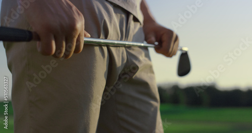Golf player swinging club putter on sunset field. Golfer stressing on sport game